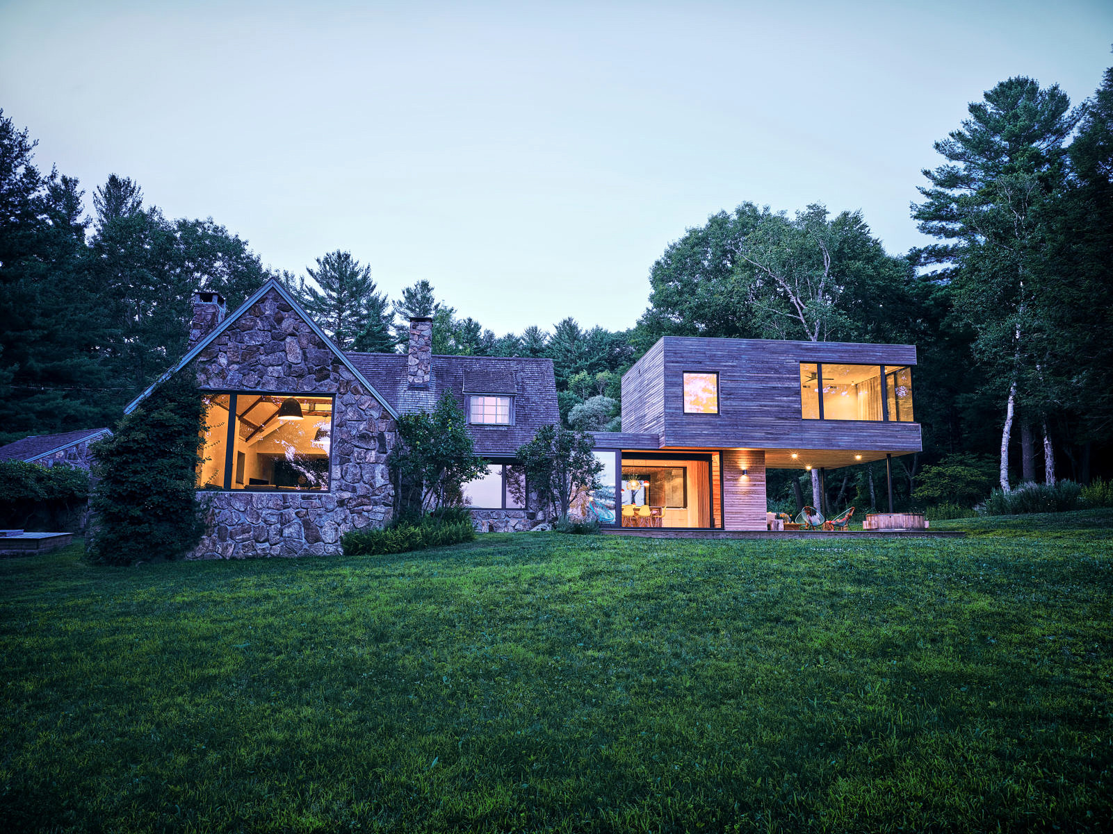 exterior view of traditional new england cottage with modern passive house addition during evening time